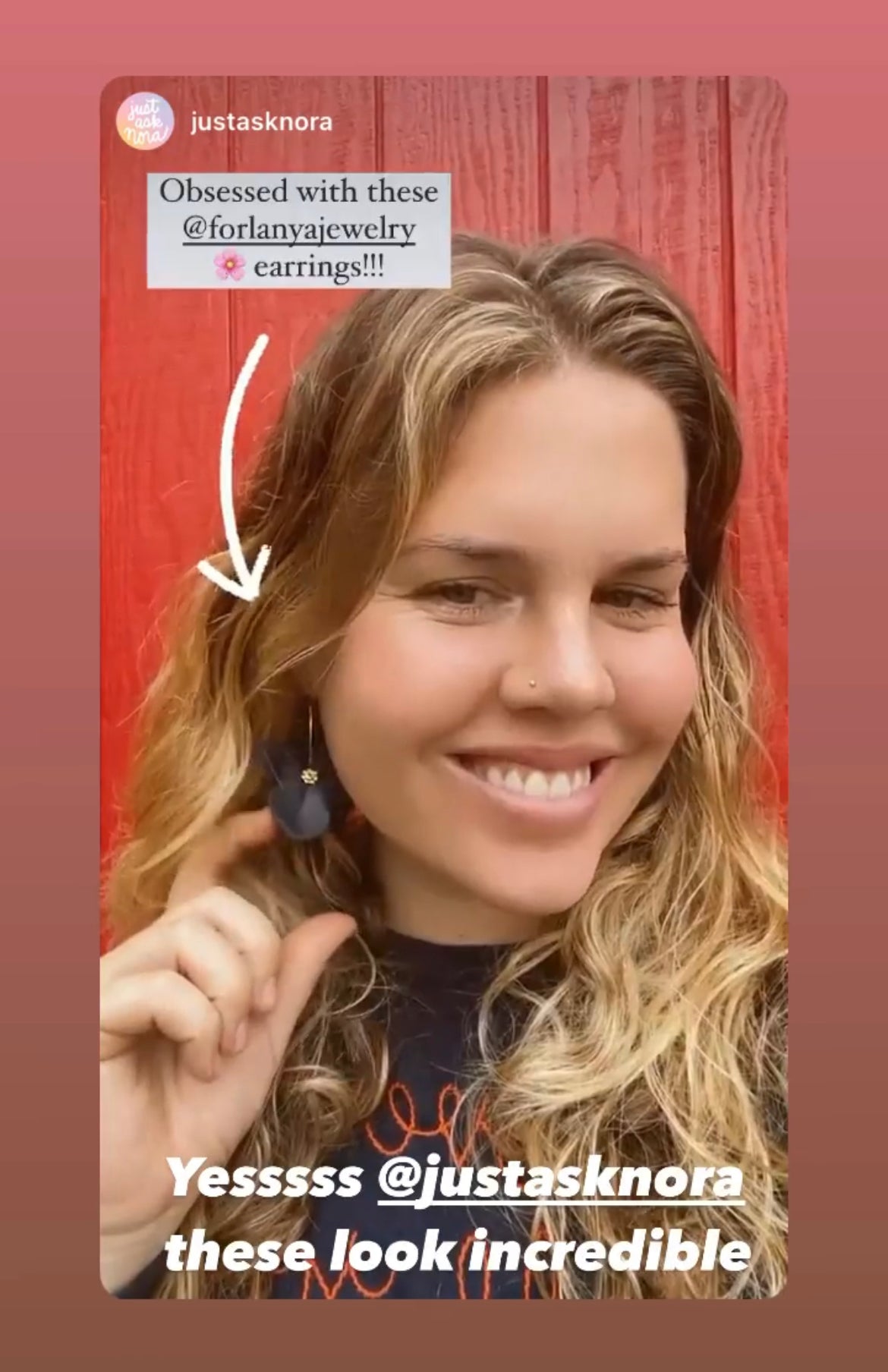Woman holding up a black earring with text expressing love for the jewelry