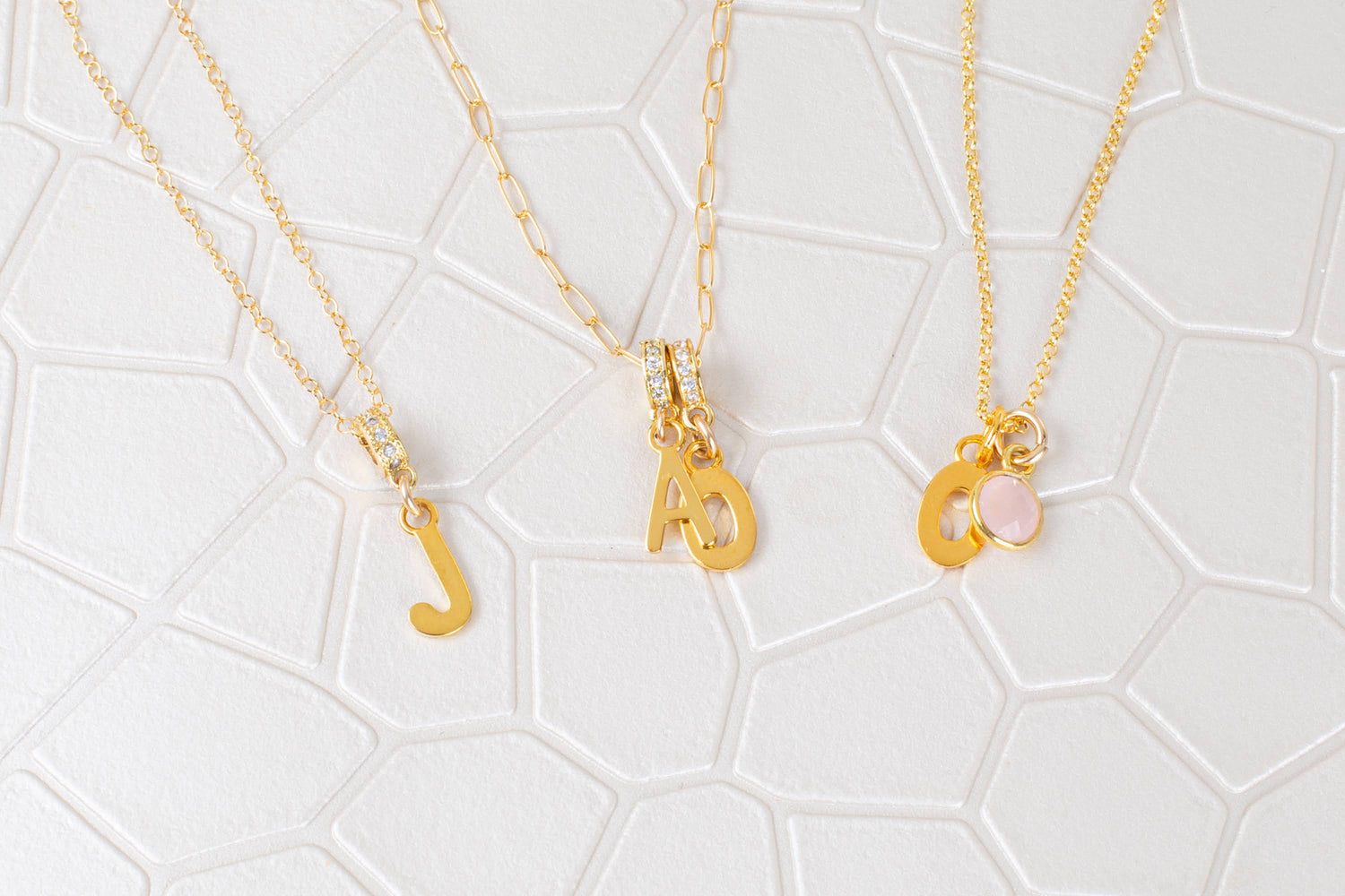 Three delicate necklaces with pendants on a white background